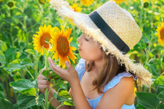 Vitamin D vs D3: girl wearing a hat smelling sunflowers