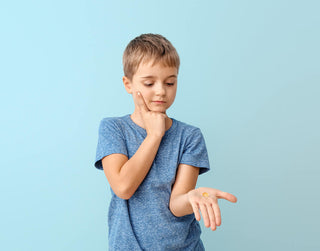 Best time of day to take vitamins: little boy looking at the pill in his hand