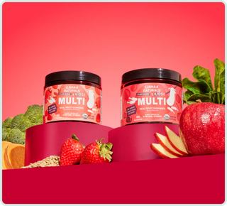 Two containers of 'Multi' supplement with fruits and vegetables on a red background