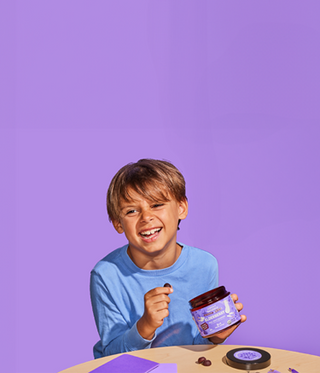 Child holding a purple container against a purple background