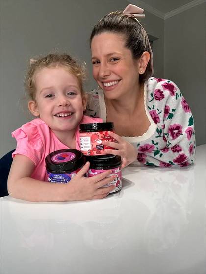 A parent and child smiling with Llama Naturals jars at a table.