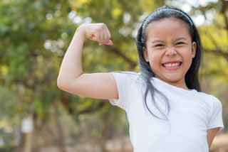 Calcium for kids: little girl showing she's strong by flexing her arm