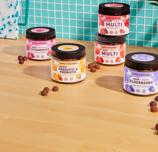Assorted health supplement jars on a wooden surface with a blue tiled wall background